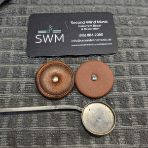 an old saxophone pad next to a new one