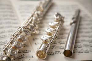 silver flute pieces on top of sheet music
